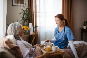 Home Health Aid Taking Care of Lady in Bed With a Chronic Condition