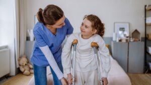 Pediatric Home Health Nurse Helping Girl in Crutches