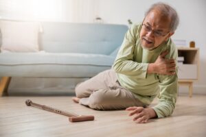 Elderly Man Who Has Fallen on the Floor and is Holding His Shoulder