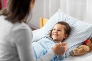 mother holding her daughter’s hands while her cheerful daughter has a winsome smile on her face