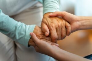 Close-up of two hands holding each other warmly