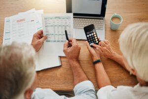 senior couple with a calculator planning financial investments, mortgage and tax papers.