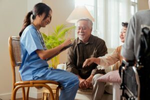 Caretakers with senior couple sitting in living room at nursing home