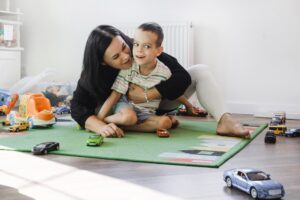 Mom Embracing Young Son with Cerebral Palsy Playing with Toy Cars
